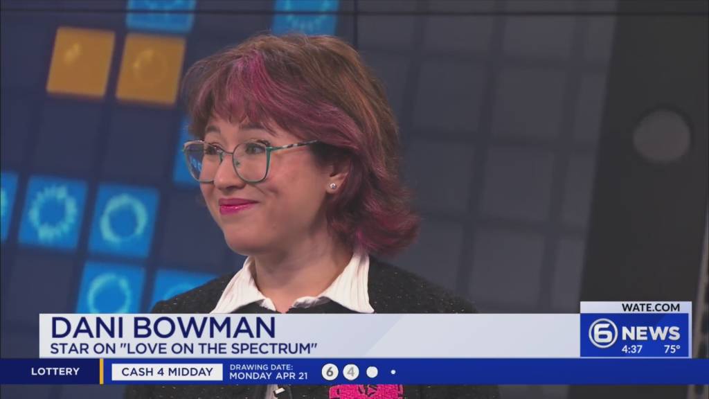 Woman with glasses and pink-streaked hair on a news set; lower third shows 'DANI BOWMAN' and 'STAR ON "LOVE ON THE SPECTRUM"'.