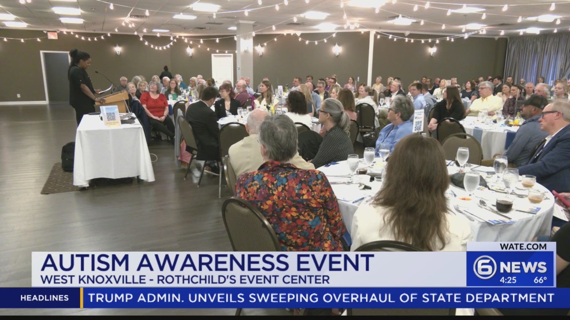 Speaker at a podium addresses a large audience at an Autism Awareness Event in a banquet hall.